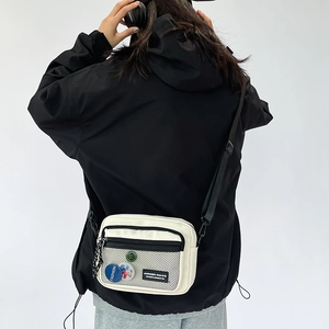 Back view of model wearing a white canvas crossbody bag with black mesh pocket and strap