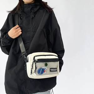 Minimalist cream canvas crossbody bag with black mesh pocket and fashion patch detail
