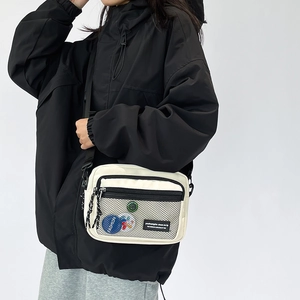 Detail of canvas crossbody bag with mesh pocket, fashion badges and adjustable strap