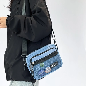 Detail of blue nylon crossbody bag with mesh pocket and adjustable shoulder strap