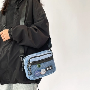 Detail of blue nylon crossbody bag featuring mesh pocket and fashion street badges