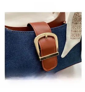 Détail du sac patchwork en denim et cuir marron avec boucle dorée et foulard