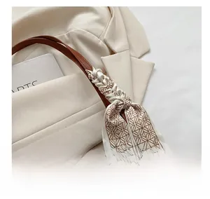 Détail d'un sac en denim avec bandoulière en cuir brun et foulard en soie décoratif