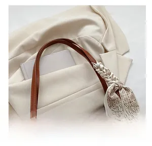 Détail du sac bandoulière en denim avec poignée en cuir et foulard en soie décoratif