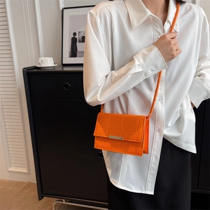 Chic orange crossbody flap bag with geometric stitching and gold buckle on female model