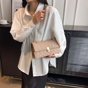 Chic beige quilted square bag with gold chain and turn-lock closure on white shirt