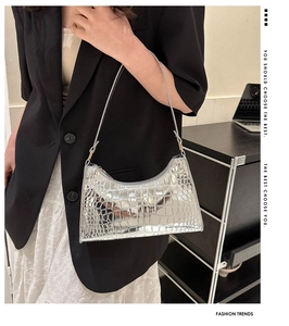 Detail of silver crocodile-embossed crescent bag with glossy mirror finish