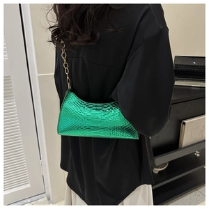 Close-up of bright green faux snakeskin baguette bag with elegant gold chain strap