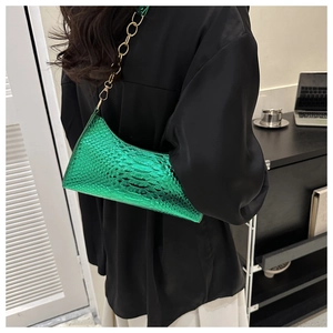 Detail view of emerald green crocodile embossed texture on a crescent moon underarm bag
