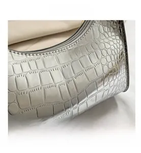 Close-up of silver croc-embossed patent leather bag with metallic finish and metal zipper
