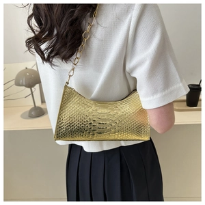 Golden faux snake leather underarm bag with thick metal chain shown on model in modern setting