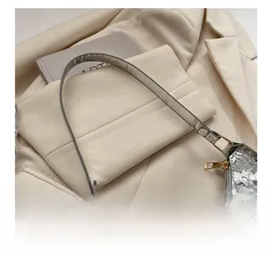 Detail of silver crocodile pattern texture on minimalist patent leather underarm bag