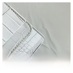 Gros plan d'un sac à main blanc gaufré crocodile avec des coutures de haute qualité