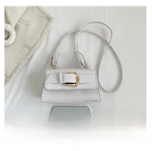 Détail du sac à main blanc motif crocodile avec boucle dorée et poignée supérieure