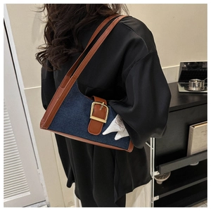 Détail du sac à épaule en denim avec garniture en cuir marron et foulard en soie décoratif