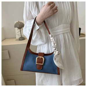 Détail du sac sous l'aisselle en denim et cuir marron avec boucle dorée et foulard en soie