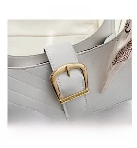 Detail of grey quilted shoulder bag featuring a large gold buckle and decorative silk scarf