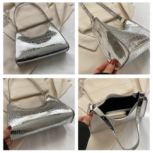 Detailed views of silver crocodile embossed patent leather bag with zipper and inner lining