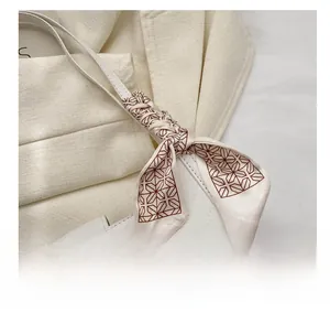 Detail of silk scarf with geometric star pattern wrapped around a white leather bag handle