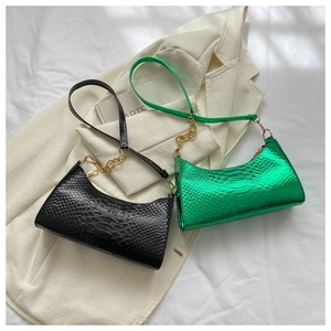 Detail shot of black and metallic green snakeskin embossed underarm bags with gold chain