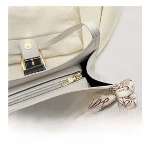 Close-up of white quilted handbag featuring gold zipper detail and silk scarf handle decor