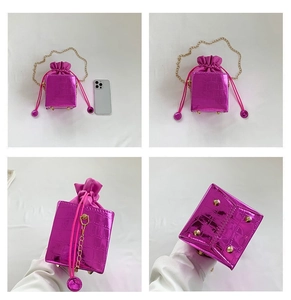 Dettaglio borsa a secchiello rosa coccodrillo con catena dorata e chiusura a coulisse