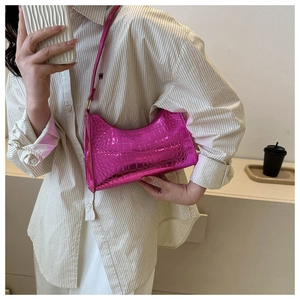 Detail of bright pink patent leather underarm bag with crocodile embossed texture