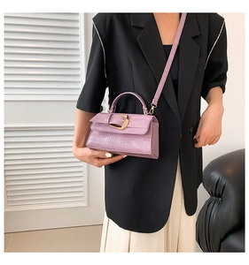 Sac bandoulière lilas à motif crocodile avec boucles dorées porté par un mannequin
