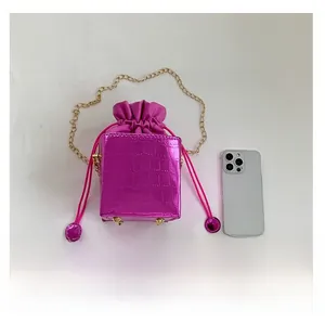 Dettaglio borsa a secchiello fucsia coccodrillo con catena d'oro e coulisse chiusura