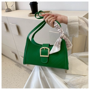 Close-up of vibrant green handbag with large gold buckle and silk scarf handle detail