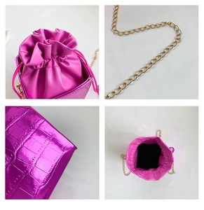 Dettaglio borsa a secchiello fucsia effetto coccodrillo con catena d'oro e chiusura a coulisse