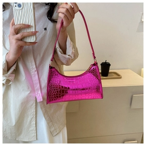 Detailed macro view of glossy rose red faux crocodile leather texture on the hobo bag