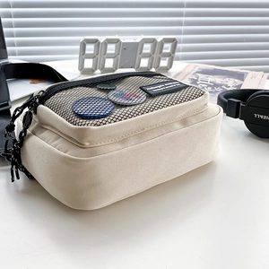 Minimalist cream canvas crossbody bag with mesh pocket and black adjustable strap detail