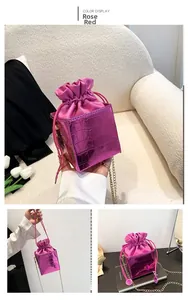 Dettagli della borsa a secchiello rosa con trama a coccodrillo e tracolla a catena d'oro
