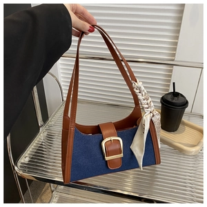 Détail d'un sac bandoulière en denim bleu avec finitions cuir brun et foulard vintage