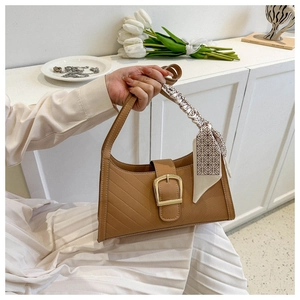 Detail of camel retro underarm bag with geometric quilting and decorative silk scarf handle