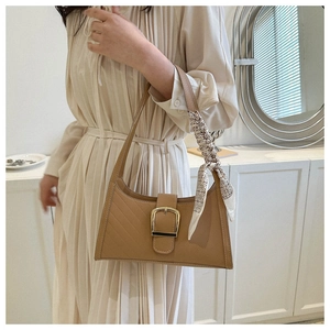 Detail of tan faux leather handbag with quilted stitching and silk scarf accessory