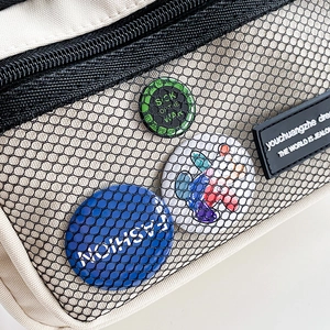 Close-up of minimalist canvas bag with mesh pocket and decorative badges