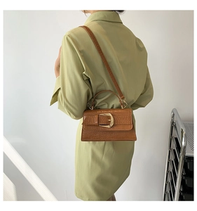 Sac à main marron effet crocodile porté en bandoulière par un mannequin en robe verte