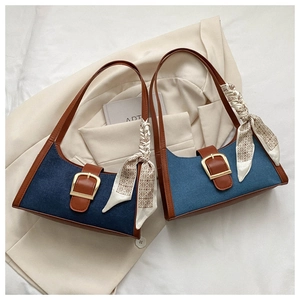 Détail du sac en jean avec poignées en cuir marron et foulard décoratif en soie imprimé