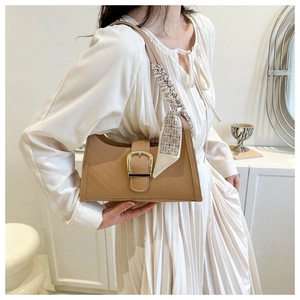 Close-up of beige quilted leather shoulder bag with gold buckle and chic silk scarf detail