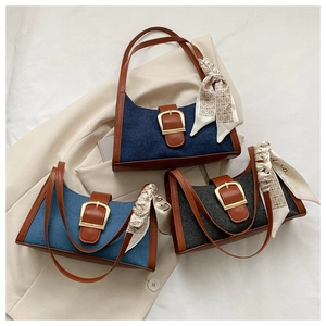 Détail du sac en denim et cuir avec boucle en fer à cheval dorée et foulard en soie