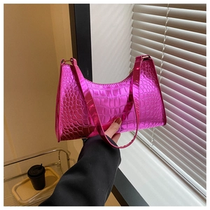 Detail of metallic pink faux leather handbag with crocodile pattern and golden hardware
