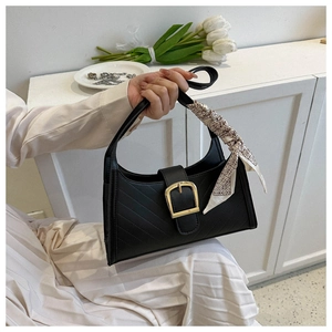 Detail of black leather shoulder bag with gold buckle, quilted stitching and silk scarf