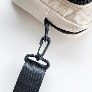 Close-up of durable black nylon strap hook and beige canvas fabric detail on a bag