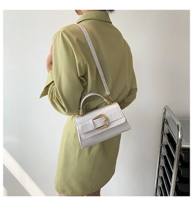 Détail du sac à bandoulière blanc motif crocodile avec boucle carrée dorée sur le côté