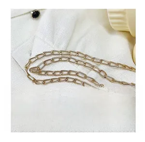 Detailed close-up of premium golden metal chain strap on white knitted fabric background
