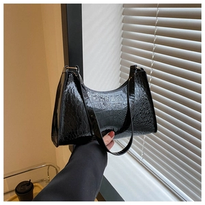 Detail of black glossy faux crocodile patent leather hobo bag with gold metal ring