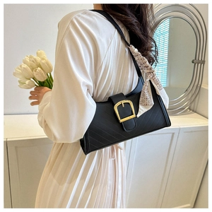 Detail of black quilted shoulder bag with gold buckle and chic patterned silk scarf wrap