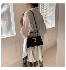 Détail du sac en cuir à motif crocodile noir avec une grande boucle carrée dorée